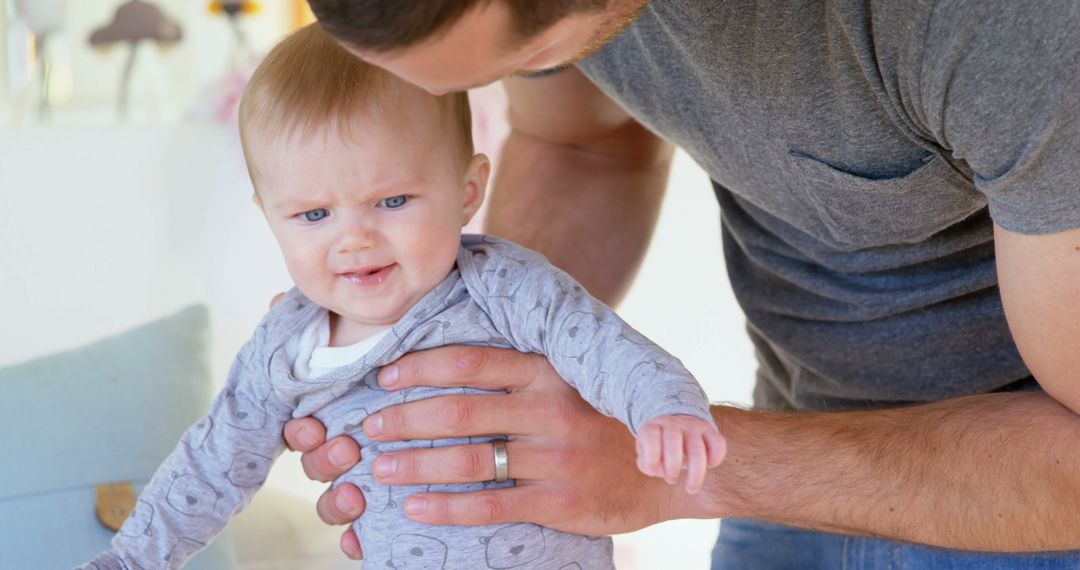 Father Supporting Baby's First Steps at Home