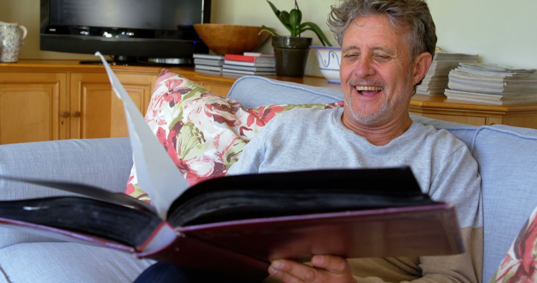 Joyful Senior Man Reading Large Book at Home - Free Images, Stock Photos and Pictures on Pikwizard.com