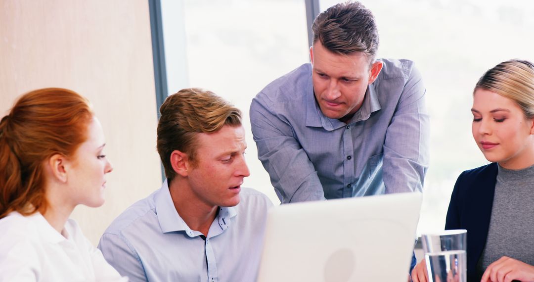 Team Discussing Project Strategies Around Laptop in Office Meeting