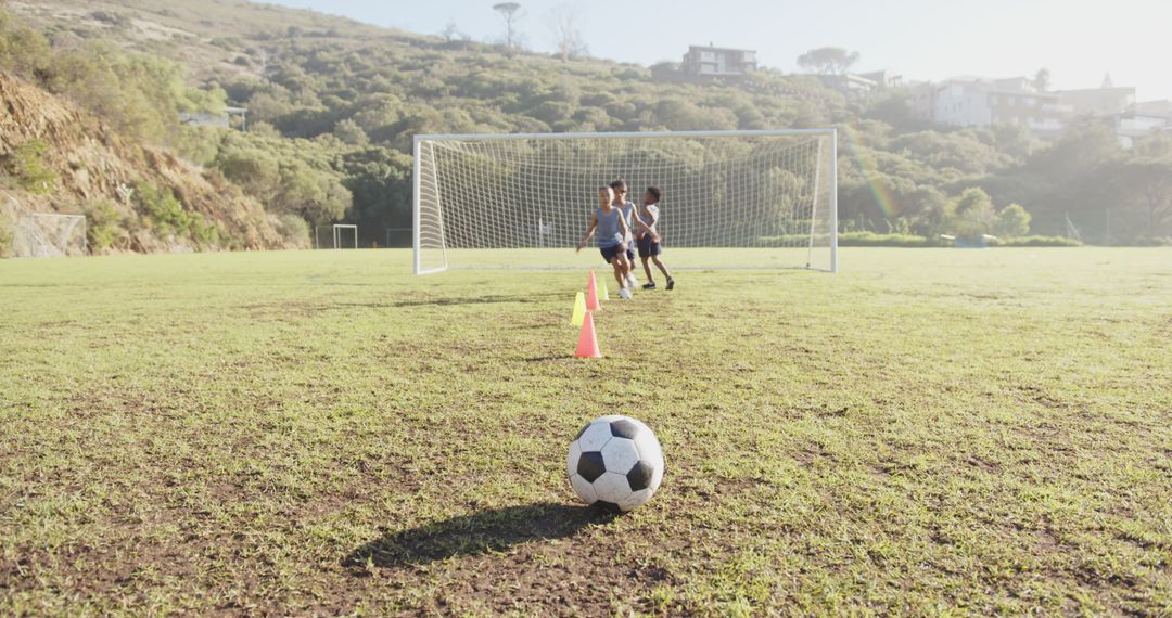 Children Playing Soccer on Sunny School Field with Goalposts