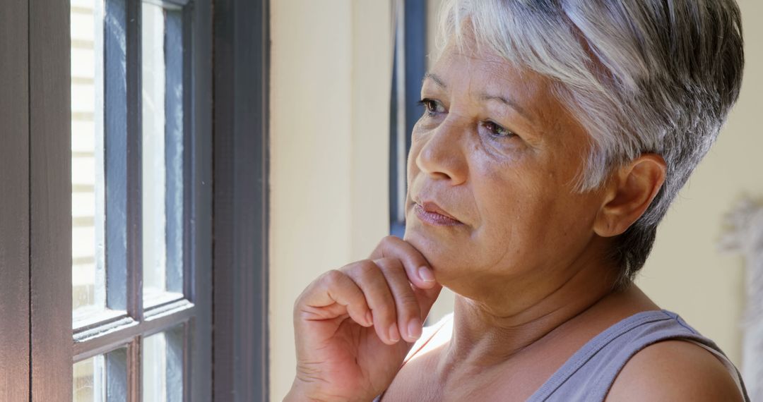 Contemplative Mature Woman Gazing Out Window in Deep Thought - Free Images, Stock Photos and Pictures on Pikwizard.com