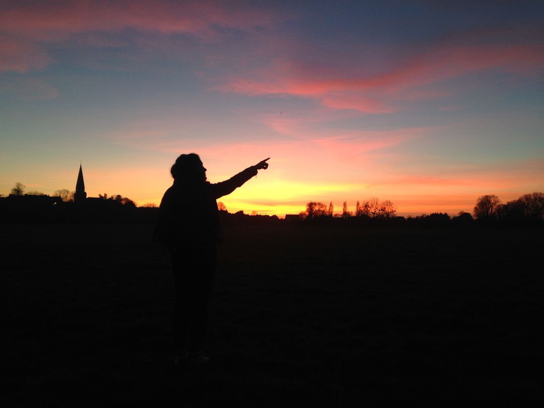 Silhouette of Person Pointing Towards Sunset with Vibrant Sky - Free Images, Stock Photos and Pictures on Pikwizard.com