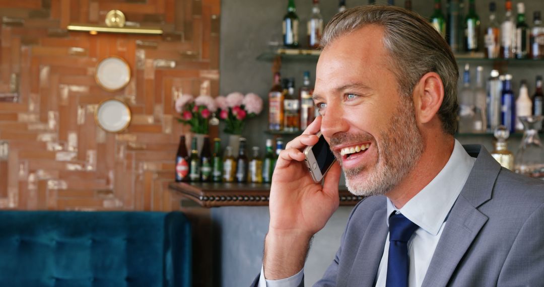 Confident Businessman Talking on Smartphone in Modern Bar - Free Images, Stock Photos and Pictures on Pikwizard.com