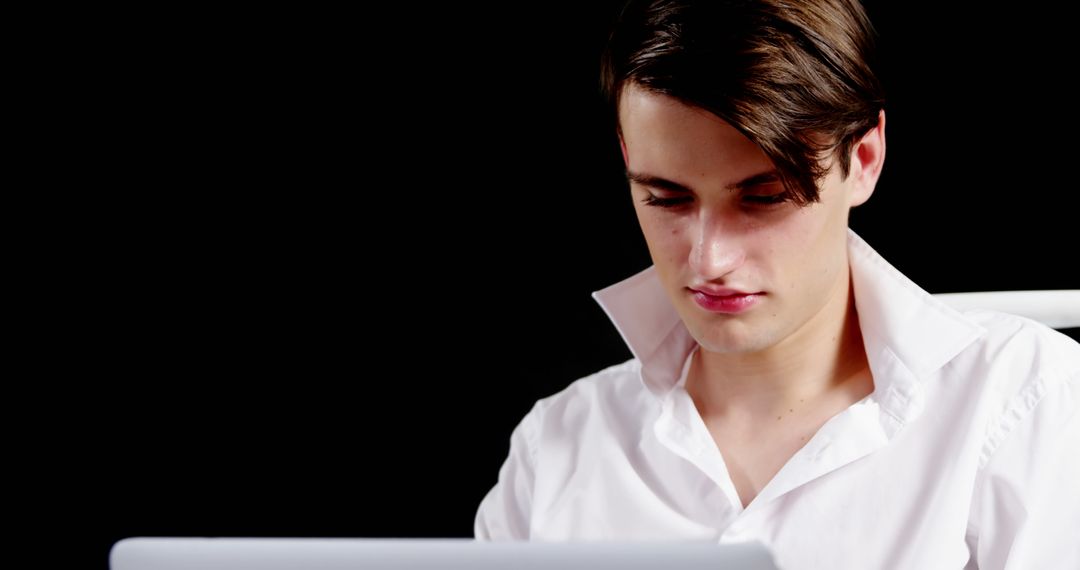 Young Man Focused on Laptop Work Against Black Background - Free Images, Stock Photos and Pictures on Pikwizard.com