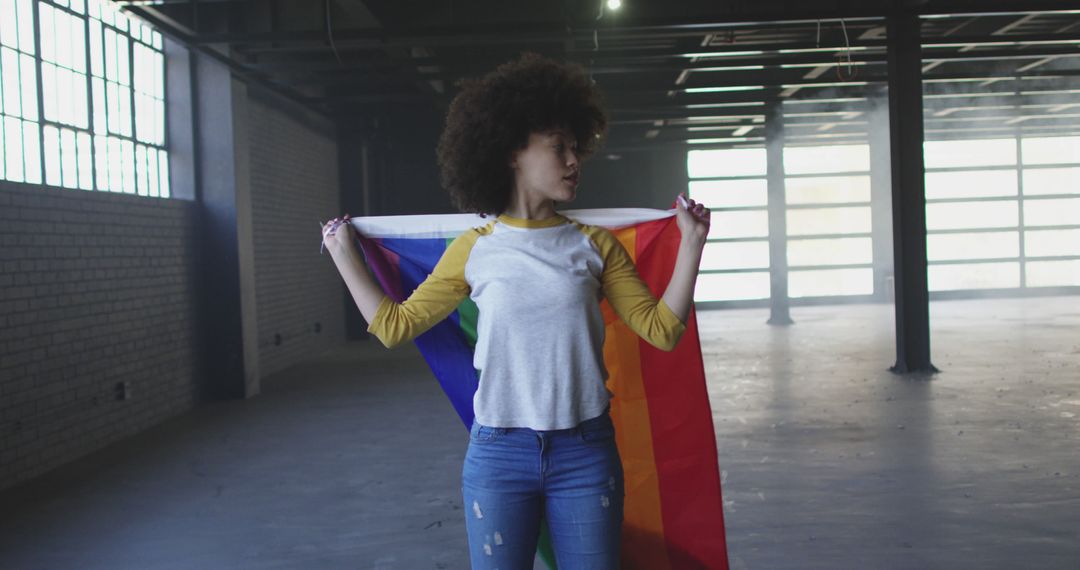 Young Woman Holding Rainbow Pride Flag in Empty Warehouse - Free Images, Stock Photos and Pictures on Pikwizard.com