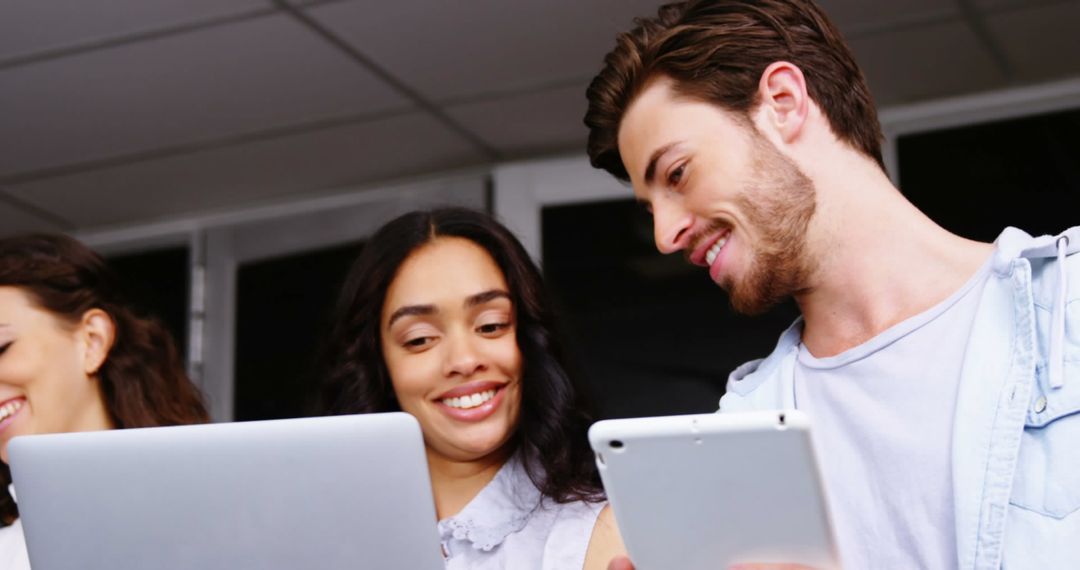 Diverse Young Professionals Collaborating on Digital Devices in Office
