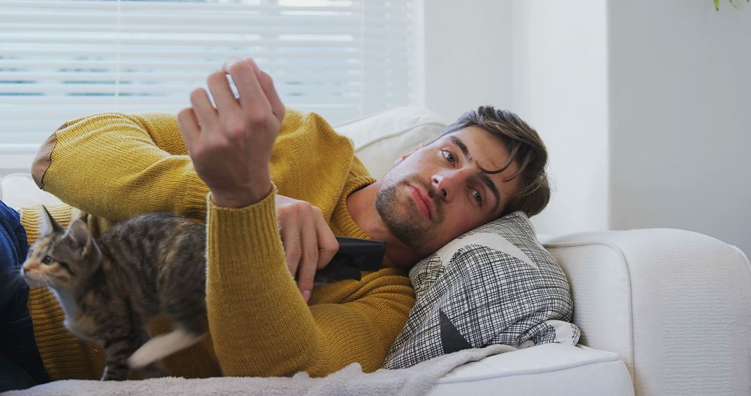 Young Man Relaxing on Sofa with Cat in Cozy Home Environment