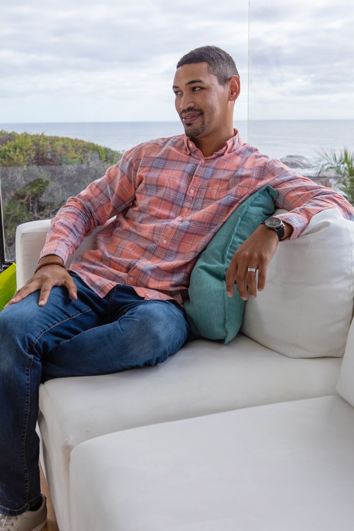 Man Relaxing on White Sofa with Ocean View