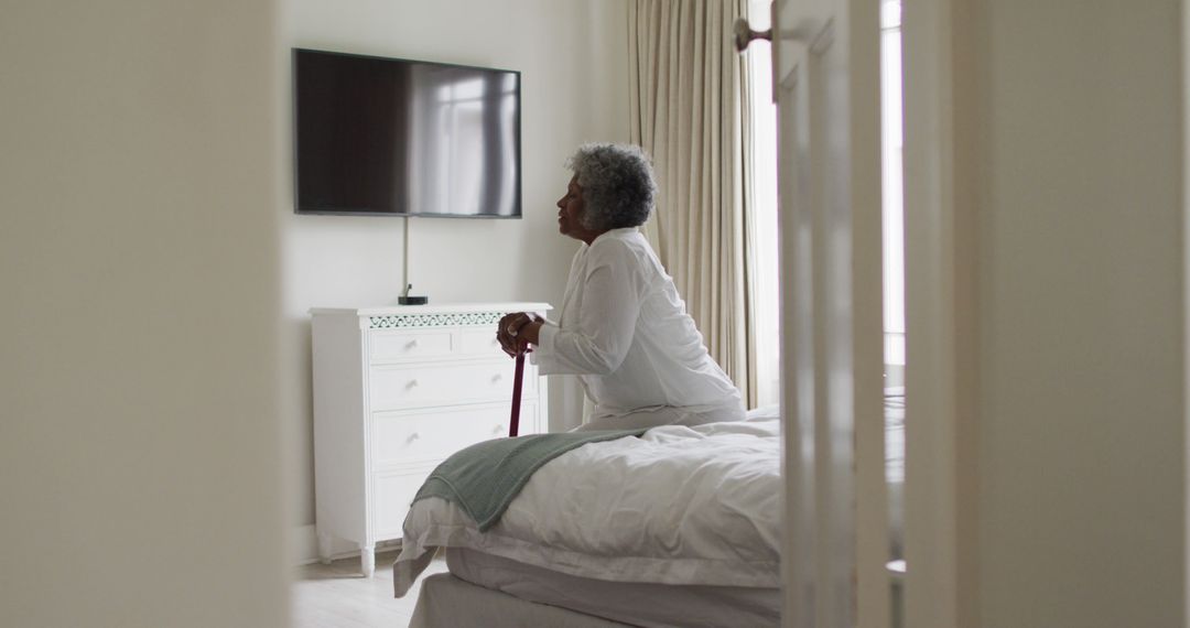 Elderly Woman Sitting on Bed with Walking Cane - Free Images, Stock Photos and Pictures on Pikwizard.com