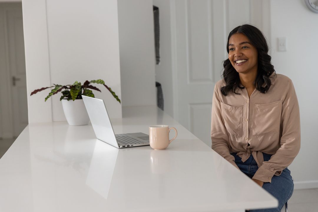 Smiling Woman Using Laptop in Bright Minimalist Kitchen
