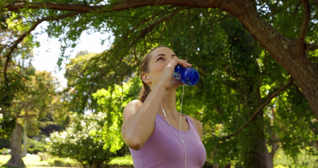 Jogger Refreshes with Water in Sunny Park - Free Images, Stock Photos and Pictures on Pikwizard.com