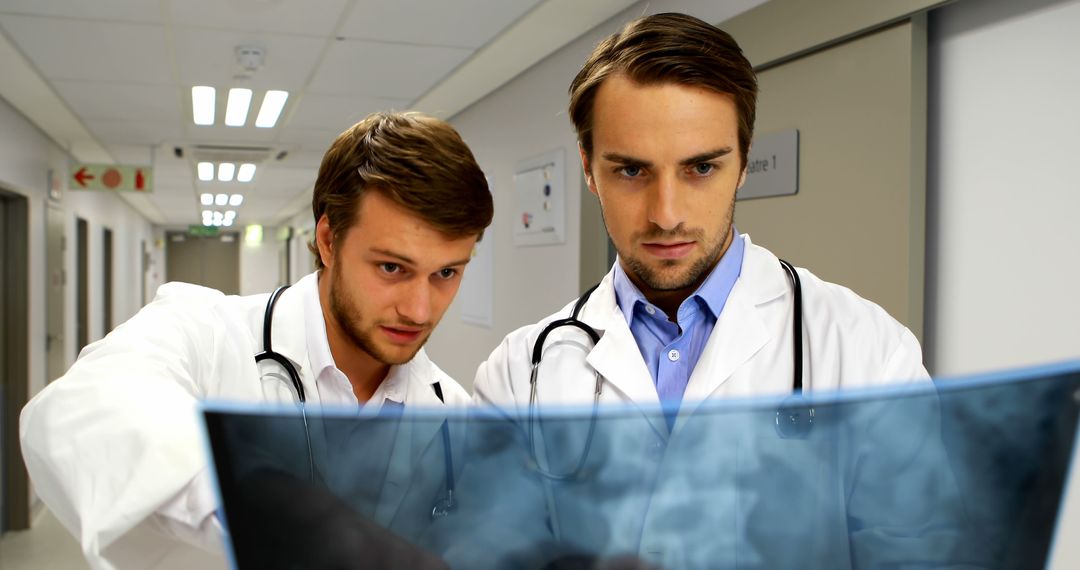 Young doctors analyzing X-ray results in hospital corridor - Free Images, Stock Photos and Pictures on Pikwizard.com