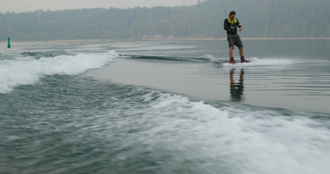 Man wakeboarding on calm lake with forested background - Free Images, Stock Photos and Pictures on Pikwizard.com