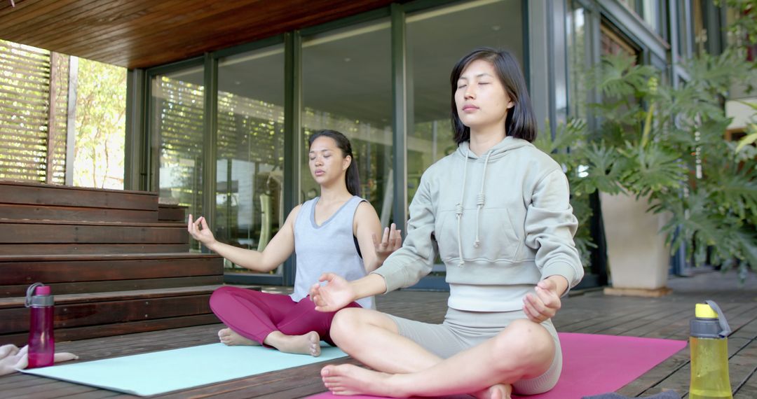 Two Women Practicing Yoga Meditating Outdoors on Wooden Deck - Free Images, Stock Photos and Pictures on Pikwizard.com