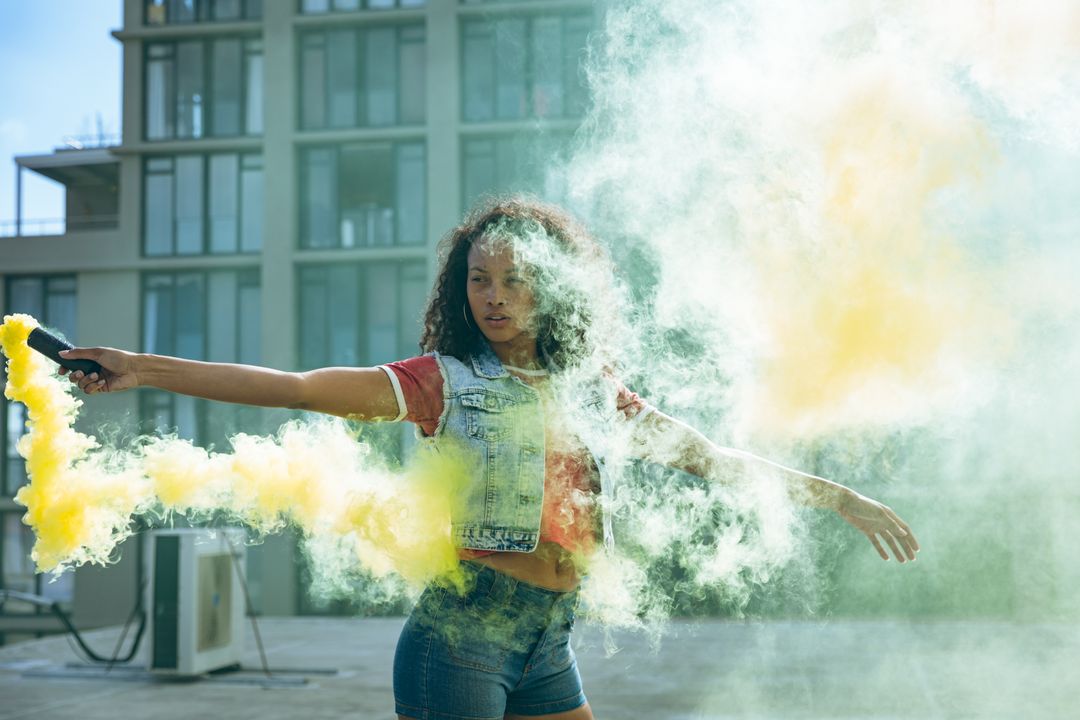 Young biracial woman holding a smoke grenade - Free Images, Stock Photos and Pictures on Pikwizard.com