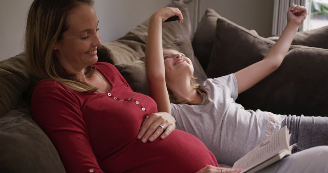 Pregnant Mother Reading to Daughter Relaxing on Couch - Free Images, Stock Photos and Pictures on Pikwizard.com