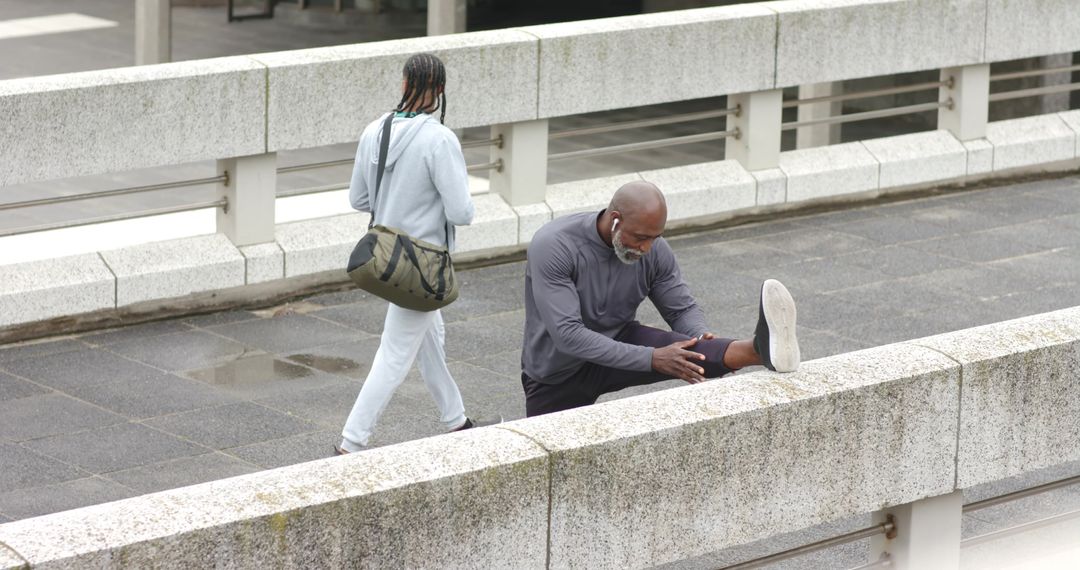 Man Stretching on Urban Overpass Rail While Passerby Walking in Light Drizzle