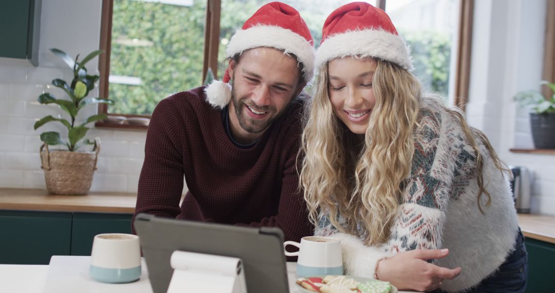 Couple Enjoying Holiday Video Call with Santa Hats in Cozy Kitchen - Free Images, Stock Photos and Pictures on Pikwizard.com