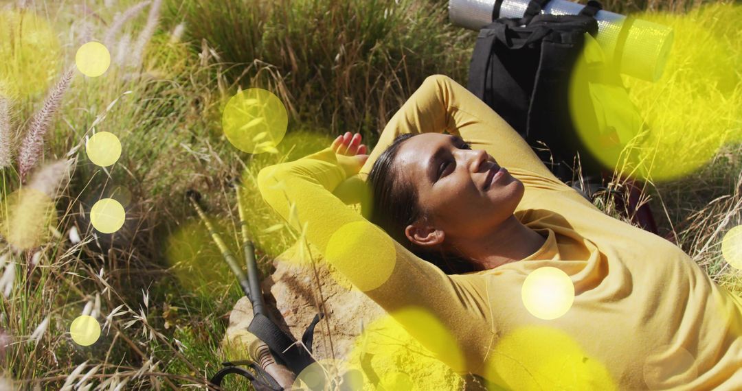 Woman Relaxing on Rock in Sunny Meadow with Camping Gear