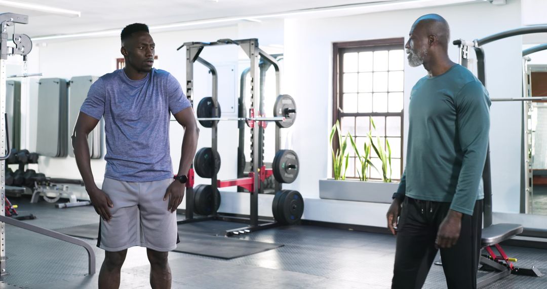 Men in Gym Engaged in Personal Training Session Near Squat Rack