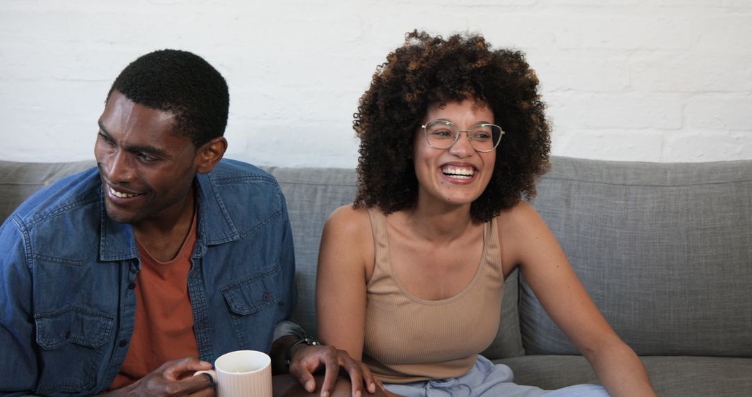 Happy Couple Relaxing on Sofa with Coffee in Living Room