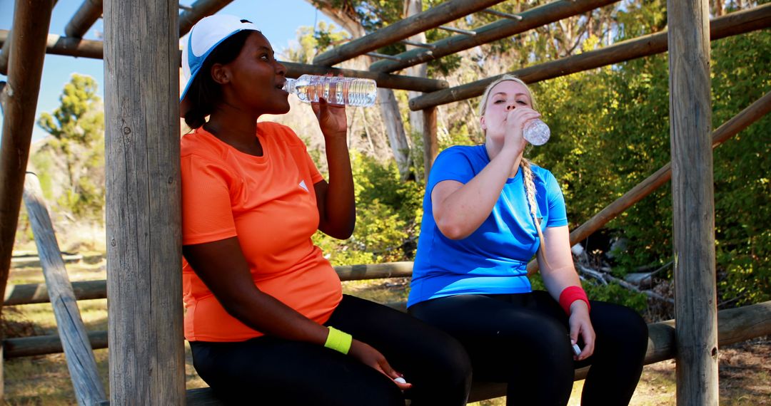 Two women taking a break and drinking water after outdoor exercise - Free Images, Stock Photos and Pictures on Pikwizard.com