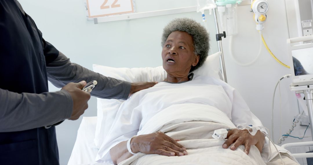 Concerned Senior Patient in Hospital Bed with Doctor Holding Medical Chart - Free Images, Stock Photos and Pictures on Pikwizard.com