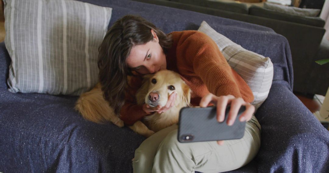 Woman Snuggling Golden Retriever Taking Selfie on Couch