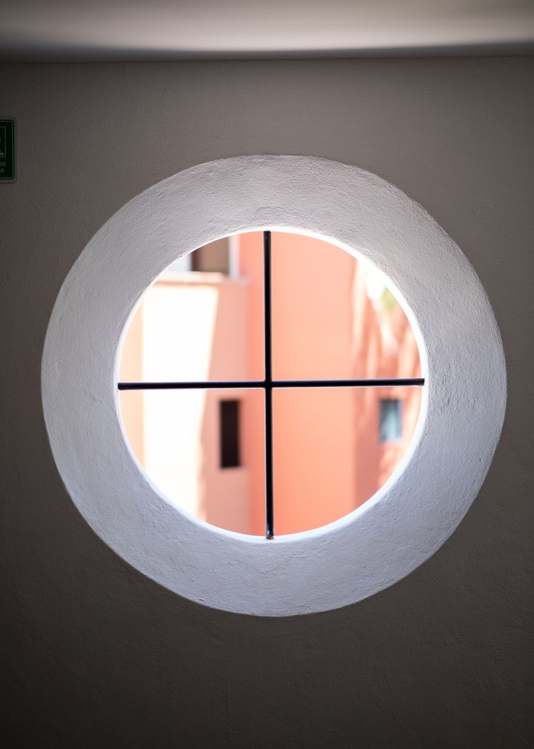 Circular window with sunlit pastel building exterior design