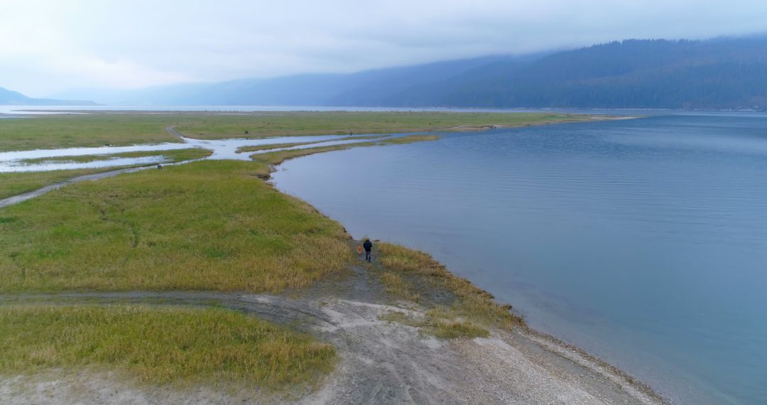 Solitary Hiker Near Mountain Lake On Cloudy Day - Free Images, Stock Photos and Pictures on Pikwizard.com