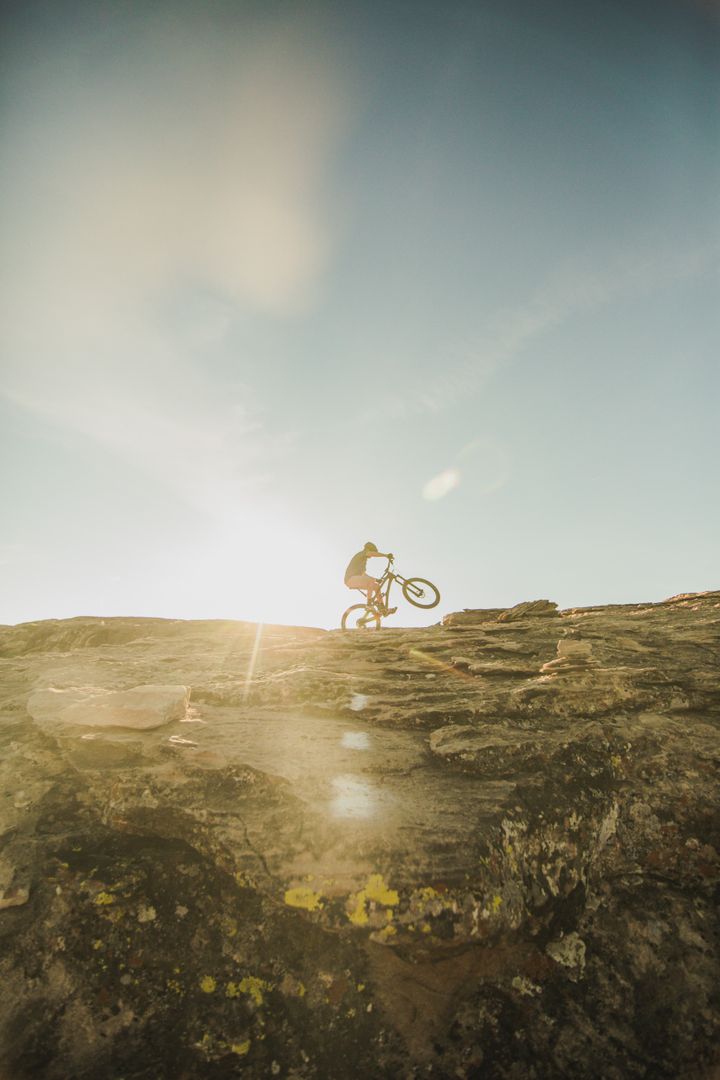 Man Cycling on Rocky Terrain with Sun Flare - Free Images, Stock Photos and Pictures on Pikwizard.com