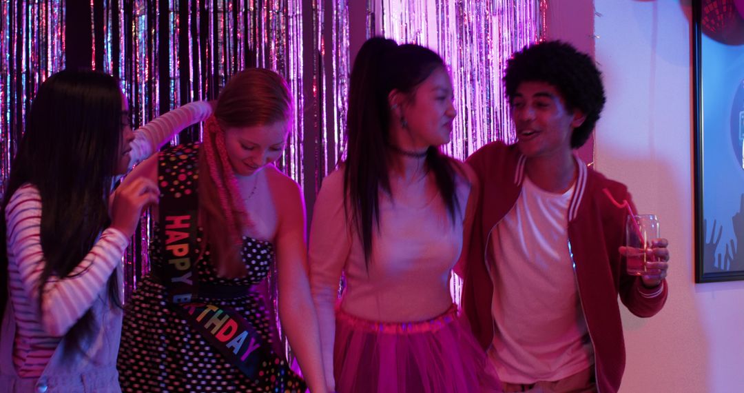 Multicultural Friends Celebrating Birthday Party With Tinsel Backdrop and Colorful Lights