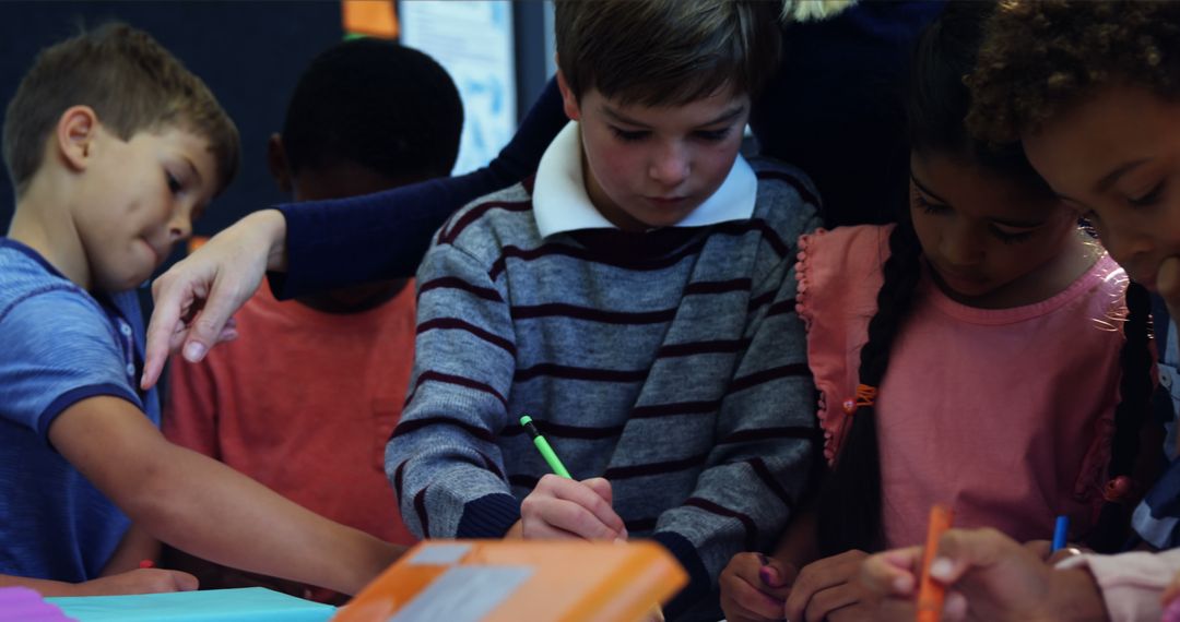 Teacher Assisting Young Students in Classroom Collaboration