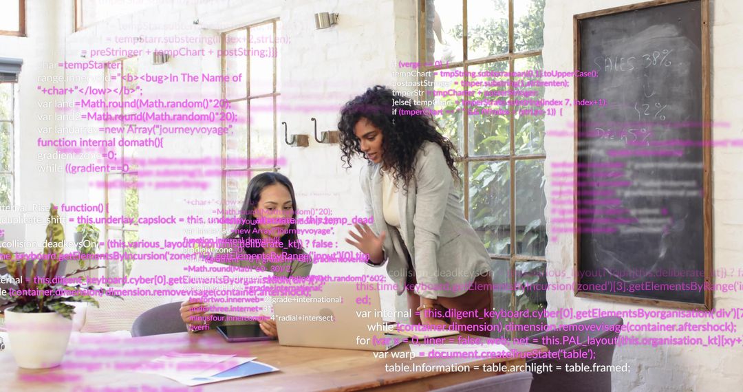 Women Collaborating Over Laptop with Code Overlay in Modern Startup Office