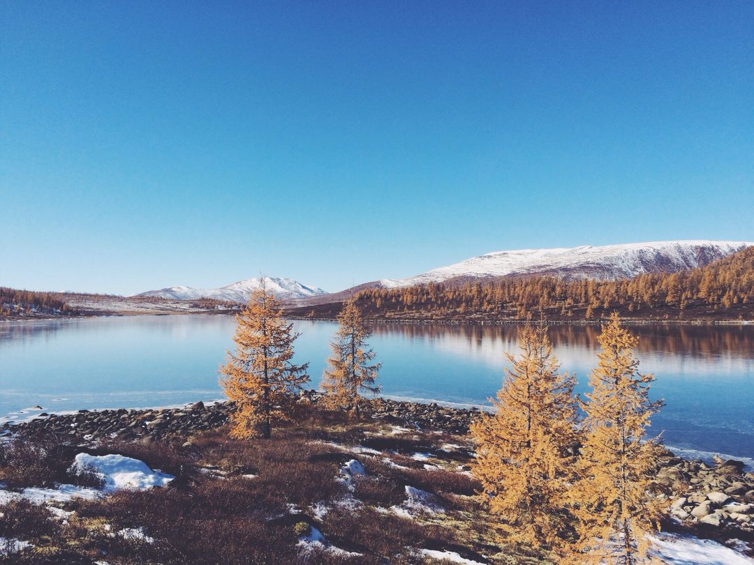 Serene Mountain Lake in Autumn with Snow-Capped Mountains and Clear Blue Sky - Free Images, Stock Photos and Pictures on Pikwizard.com