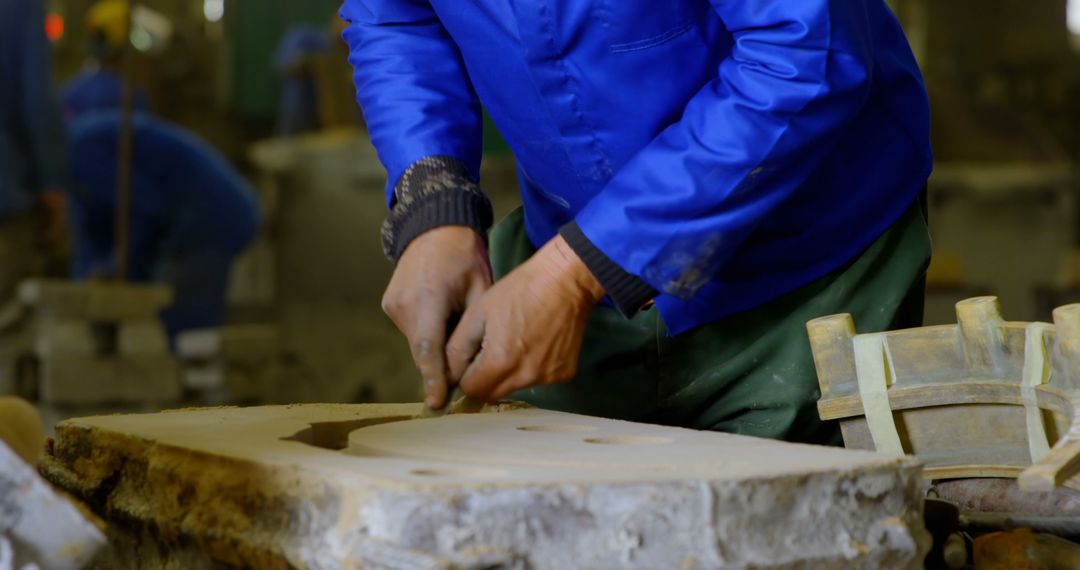 Craftsman Sculpting Stone in Workshop Wearing Blue Jacket - Free Images, Stock Photos and Pictures on Pikwizard.com