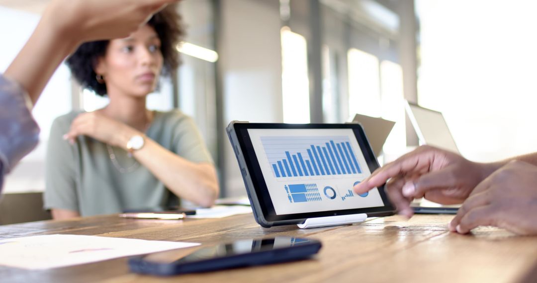 Diverse Team Analyzing Data on Tablet in Modern Meeting Room