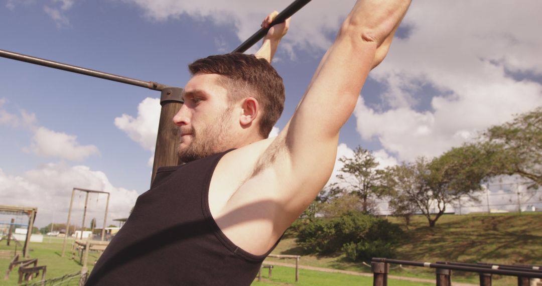 A young Caucasian man performs pull-ups at an outdoor fitness area, with copy space - Free Images, Stock Photos and Pictures on Pikwizard.com