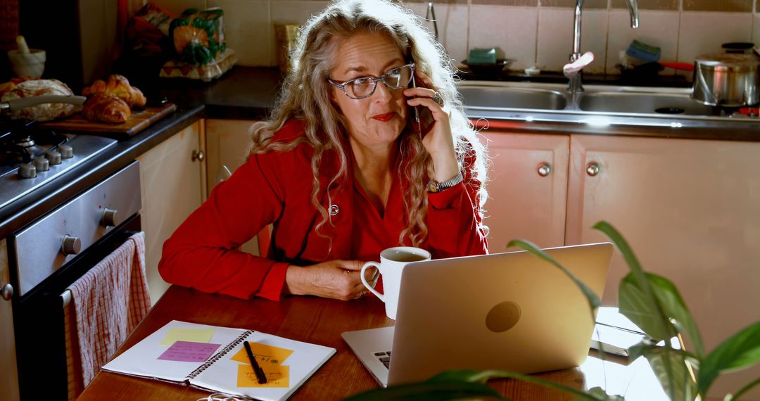 Mature Woman Working from Home in Kitchen while on Phone - Free Images, Stock Photos and Pictures on Pikwizard.com