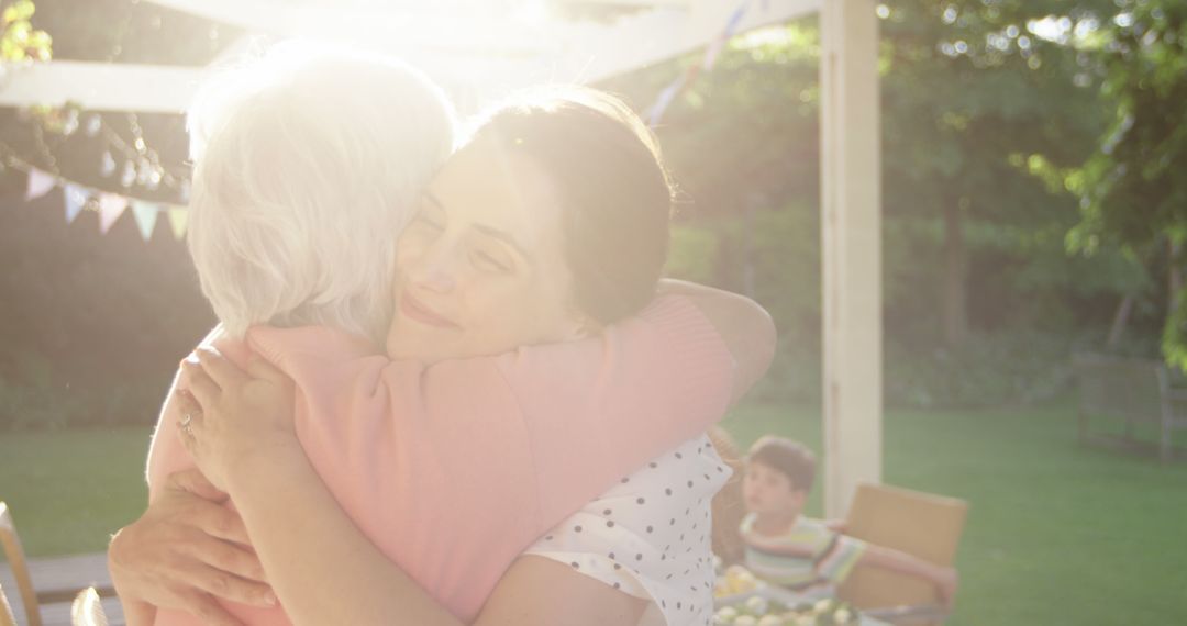 Warm Embrace Between Elderly Woman and Young Woman in Sunlit Garden - Free Images, Stock Photos and Pictures on Pikwizard.com