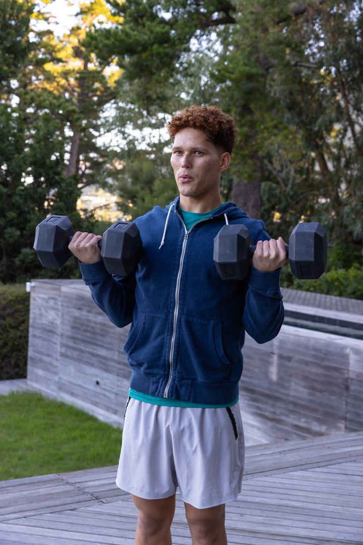 Man in Blue Hoodie Exercising with Dumbbells Outdoor