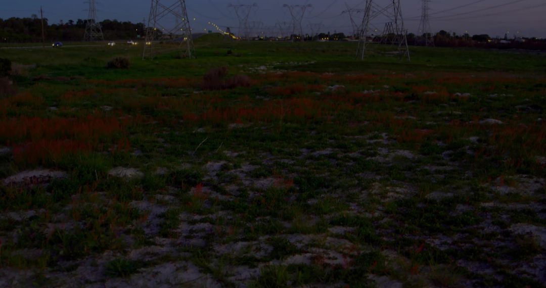 Transmission Tower and Power Lines on Grassy Fields at Dusk