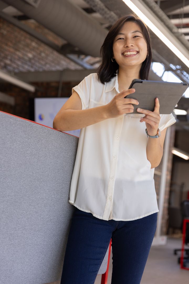 Smiling Businesswoman Using Tablet in Open-Plan Office Workspace