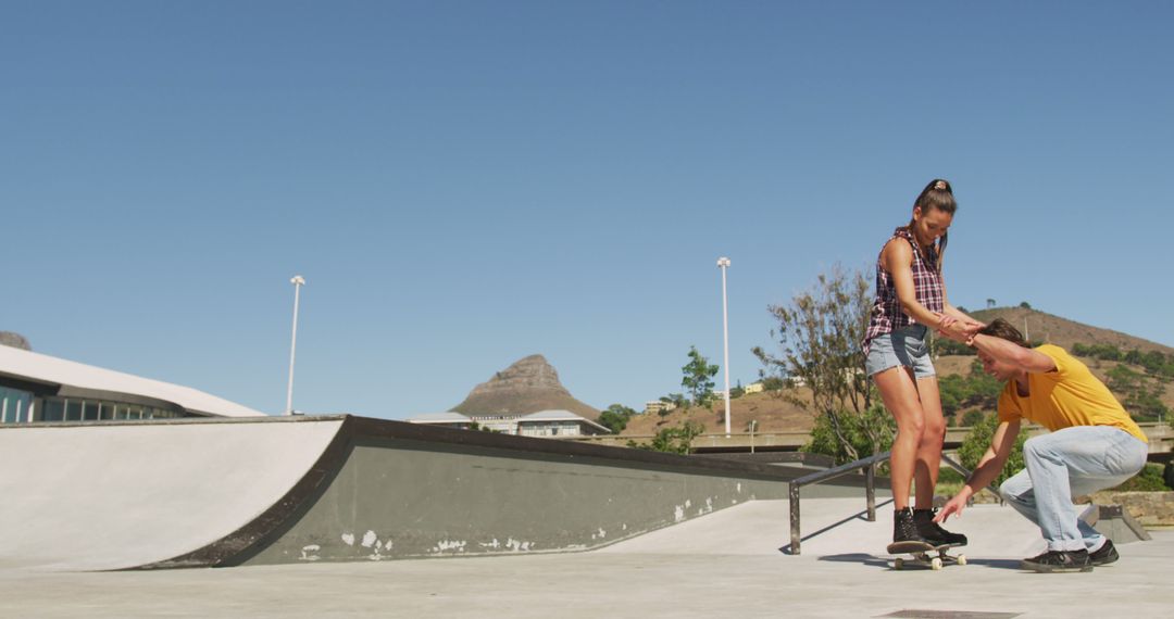 Young Man Teaching Woman Skateboarding at Outdoor Skatepark - Free Images, Stock Photos and Pictures on Pikwizard.com