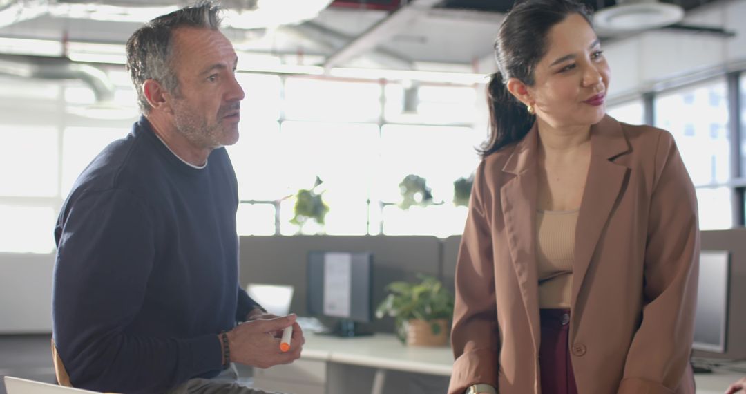 Diverse coworkers collaborating at modern open-plan workstation during team meeting