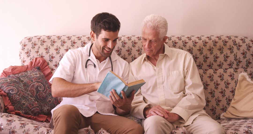 Medical Professional Reading With Elderly Man on Couch in Cozy Living Room - Free Images, Stock Photos and Pictures on Pikwizard.com