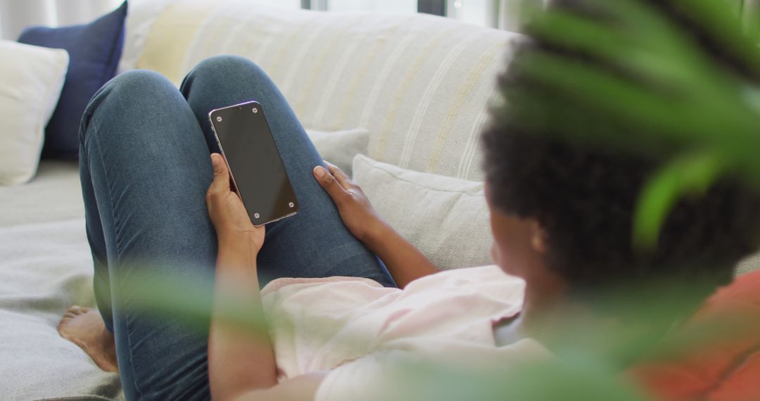 Relaxed Person Sitting on Sofa Holding Smartphone - Free Images, Stock Photos and Pictures on Pikwizard.com