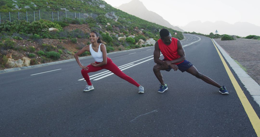 Diverse Fit Couple Stretching on Scenic Country Road near Mountains - Free Images, Stock Photos and Pictures on Pikwizard.com