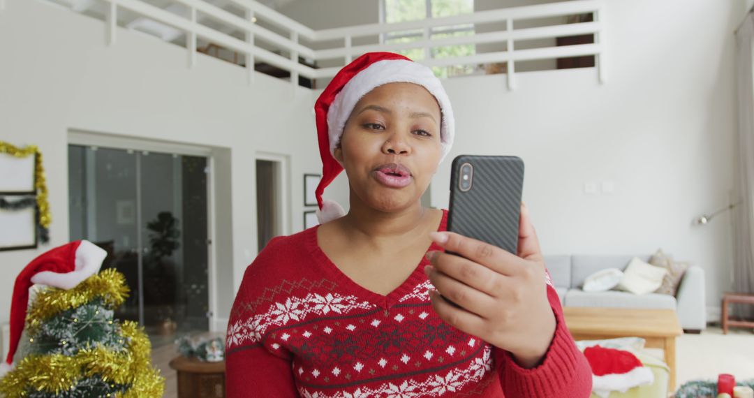 Happy african american plus size woman in santa hat, making image call on smartphone at christmas - Free Images, Stock Photos and Pictures on Pikwizard.com