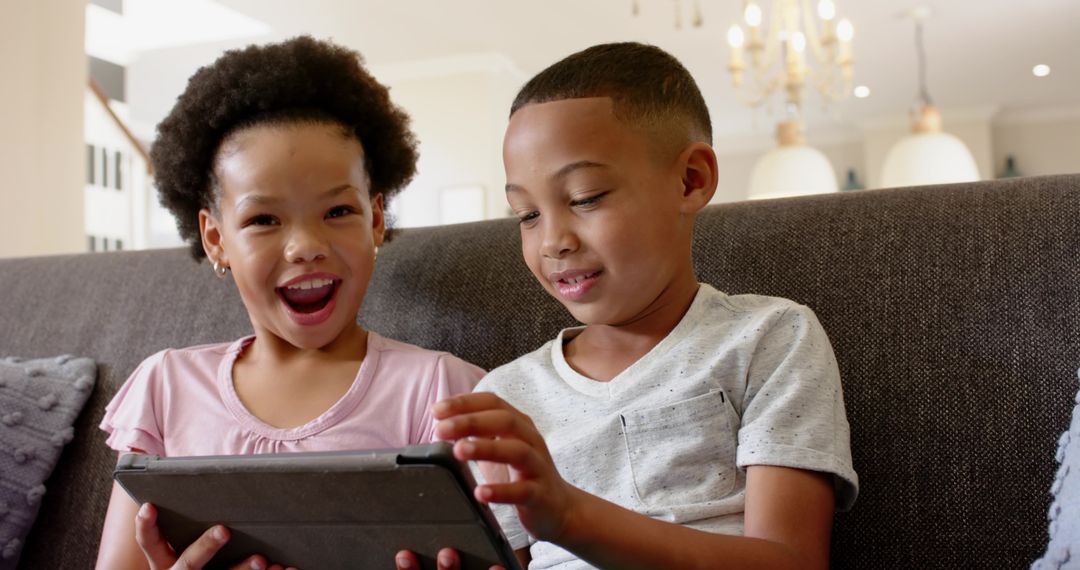 Joyful Siblings Sharing Fun on Tablet at Home